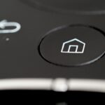 Smart Home Sicherheit im Überblick: Person konfiguriert vernetzte Geräte im Wohnzimmer.