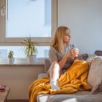 a woman sitting on a couch holding a glass of water
