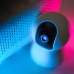 Ein Smartphone zeigt ein Dashboard mit vernetzten Sicherheitsfunktionen wie Rauchmelder, Türsensoren und Verschlüsselungssymbole.