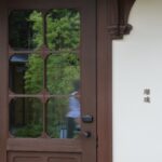 Kleiner Tür- oder Fenstersensor auf weißem Hintergrund, daneben ein Smartphone, das eine Benachrichtigung über eine geöffnete Haustür anzeigt.