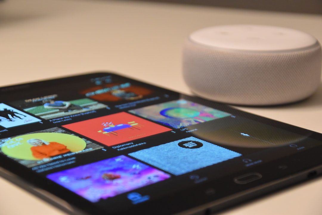 Kompakter Amazon Echo Dot in weiß auf einem Holztisch, umgeben von smarten Geräten wie einer Lampe und einem Thermostat.