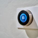 Ein elegantes, weißes SONOFF-Bedienpanel mit farbigem LCD-Touchscreen ist flach an der Wand montiert. Auf dem Display sind mehrere Smart-Home-Symbole und ein Raumtemperatur-Regler zu sehen, während eine Hand dezent auf das Panel tippt. Der Hintergrund zeigt eine moderne, minimalistische Wohnung mit warmem Licht, was die einfache und schnelle Steuerung ohne Smartphone betont.