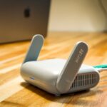Ein einzelner TP-Link Deco BE65 WLAN-Router in Weiß, modernes, schlankes Design, steht auf einem Holztisch in einem hellen, gemütlichen Wohnzimmer, umgeben von dezenten Smart-Home-Geräten, symbolisiert schnelles, stabiles Wi-Fi 7 für das ganze Zuhause.