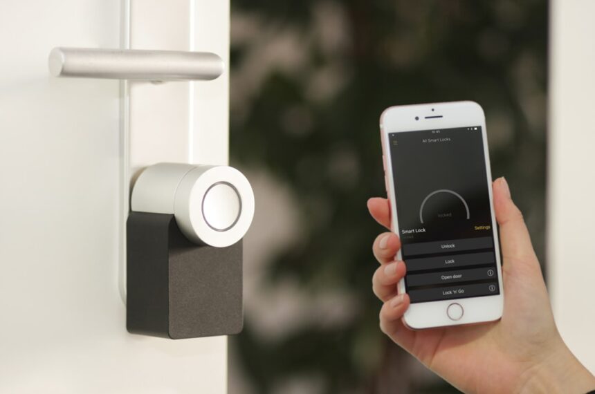 Ein schlankes, weißes Nuki Keypad mit beleuchtetem Zahlenfeld ist neben einer modernen, smarten Haustür montiert. Eine Hand tippt eine PIN ein, während die Tür leicht geöffnet ist – ein Symbol für komfortablen, schlüssellosen Zutritt im smarten Zuhause.